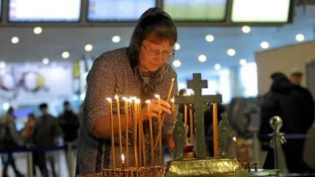 Una mujer enciende una vela, en el aeropuerto de Domodedovo.