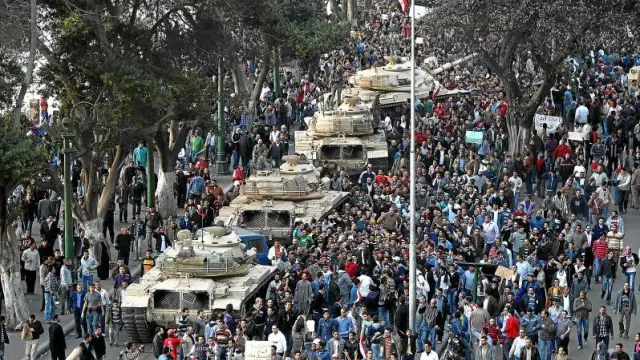 Varios tanques circulan por una calle de El Cairo rodeados por miles de egipcios.