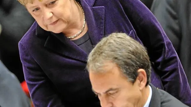 Merkel se acerca a Zapatero en el Consejo Europeo celebrado en Bruselas el 16 de diciembre.