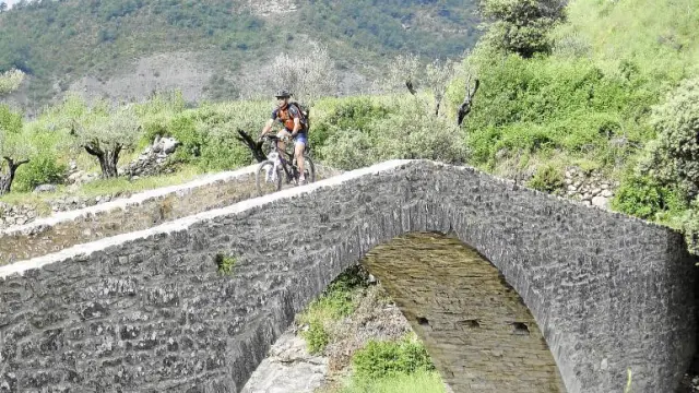 Un ciclista de BTT transita por un puente rehabilitado de la comarca de la Ribagorza donde Aramón Bike, también está presente.