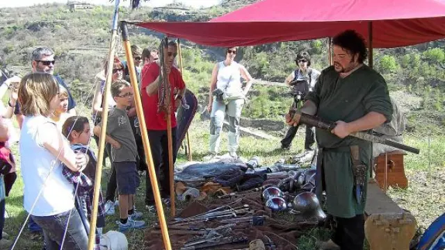 Uno de los voluntarios muestra a los visitantes y turistas el armamento de la Edad Media.