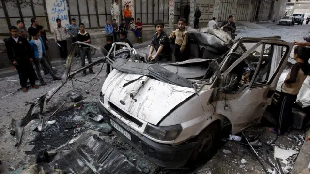 Niños juegan en un vehículo alcanzado por un bombardeo israelí