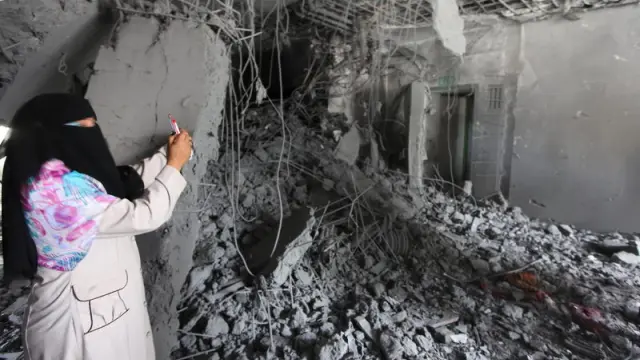 Una mujer fotografía su casa en Tripoli tras los bombardeos