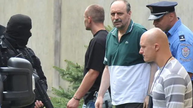 El ex militar serbio Goran Hadzic es escoltado por la policía durante su traslado a La Haya.