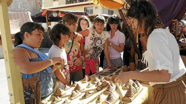 Un grupo de niños observa piezas artesanas de madera en una edición anterior de Artemon.