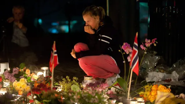 Una mujer permanece frente a las ofrendas dejadas en una iglesia de Oslo