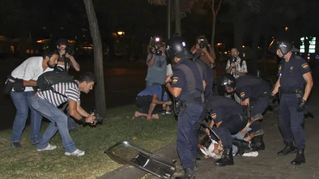 Miembros de la Policía Nacional retienen a un joven durante los disturbios de la noche del jueves