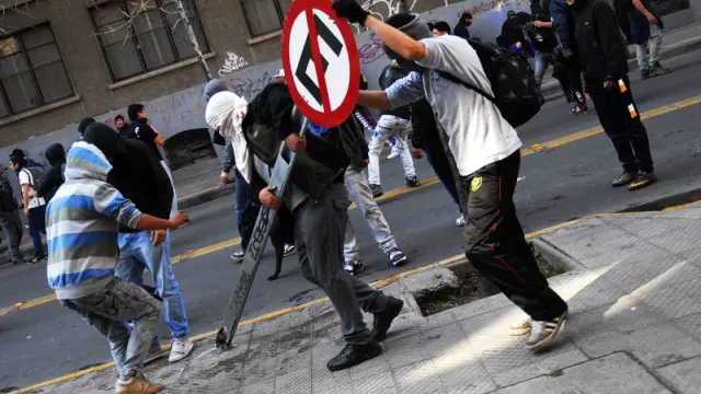 Manifestantes arrancan del suelo una señal en Santiago de Chile