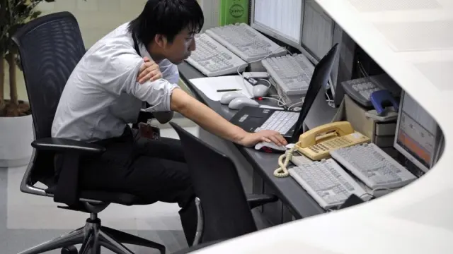 Un corredor de bolsa observa los datos bursátiles en un ordenador en la bolsa de Tokio
