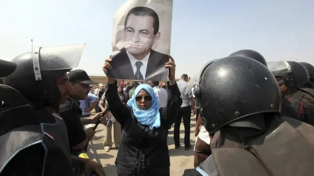 Una mujer sostiene un retrato de Mubarak en la puerta del jugzgado