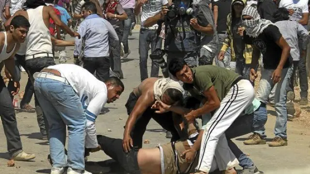 Palestinos ayudan a un hombre herido en un enfrentamiento con tropas israelíes, ayer en Qusra.