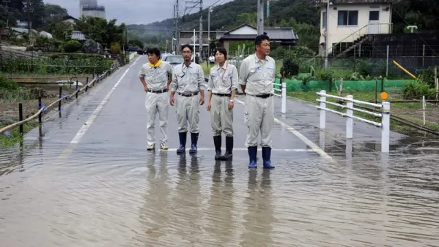 Cuatro inspectores observan una calle inundada en Iwakura