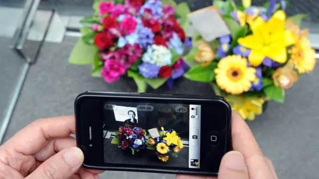 Un ciudadano toma una foto de un altar improvisado con su iPhone4