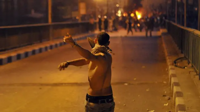 .- Un joven egipcio enfrenta a fuerzas de seguridad egipcias durante una protesta llevada a cabo frente al edificio de la radiotelevisión en El Cairo