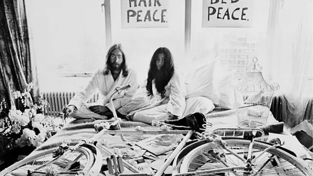 Yoko Ono y John Lennon en la cama con el cartel colgado