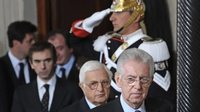 El excomisario europeo y senador italiano, Mario Monti (dcha), sale de la rueda de prensa ofrecida para presentar la lista de ministros tras aceptar el cargo de presidente del Gobierno de Italia