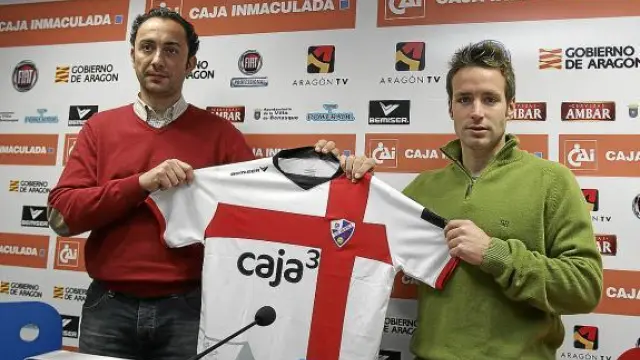 José Antonio Llamas posa junto al gerente del Huesca, Raúl Ojeda, y su nueva camiseta.