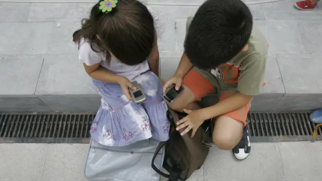 Dos niños trastean con sendos teléfonos en una imagen de archivo