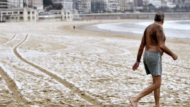 Un hombre se mete al agua en la playa de la Concha de San Sebastián