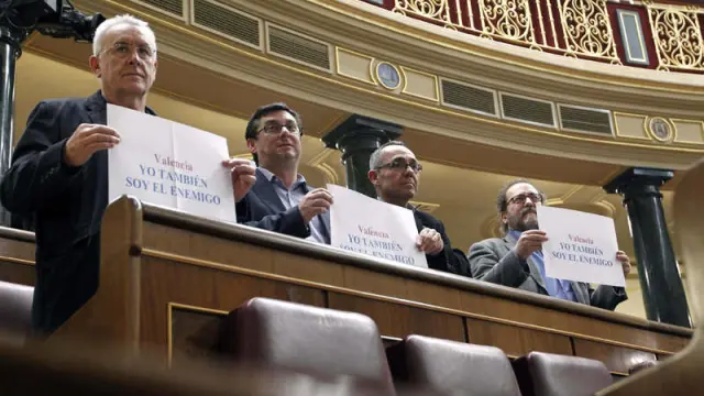 El diputado de IU, Cayo Lara, sotiene en el Congreso una pancarta que dice "Yo también soy el enemigo"