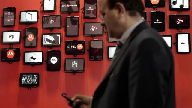 Un hombre consulta su móvil frente al stand de Motorola en el Mobile World Congress.