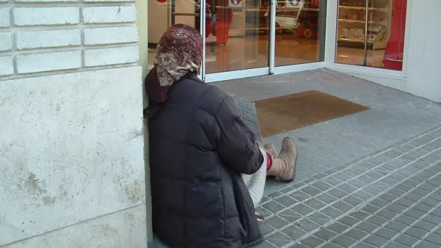 Una mujer pide limosna en la puerta de un supermercado de Huesca