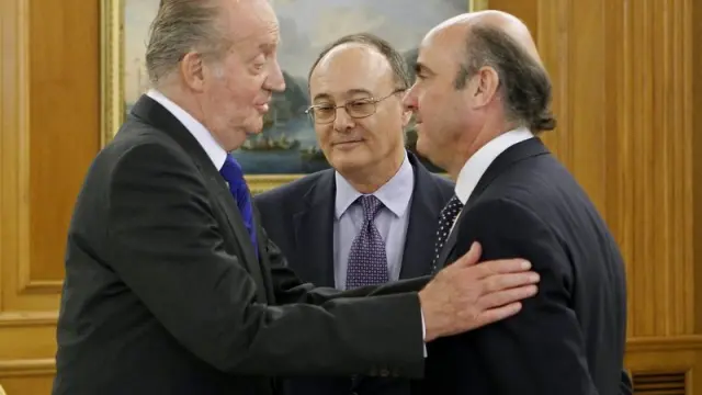 El rey Juan Carlos conversa con el ministro de Economía, Luis de Guindos (d), en presencia del nuevo gobernador del Banco de España, Luis María Linde de Castro