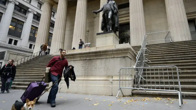 Un neoyorquino pasa con su equipaje junto a Wall Street.