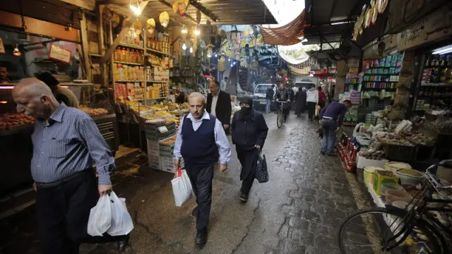 Varios sirios transitan este domingo un mercado de Damasco