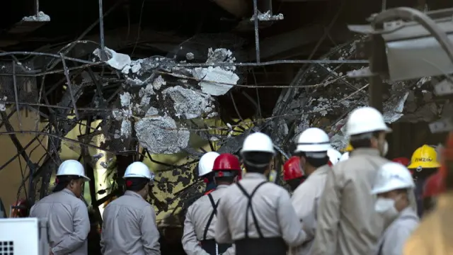 Empleados de Pemex observan los daños causados por la explosión