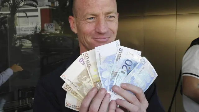 Un hombre muestra el dinero en efectivo que acaba de retirar de un banco chipriota