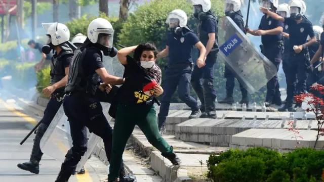 Un policía antidisturbios forcejea con una manifestante