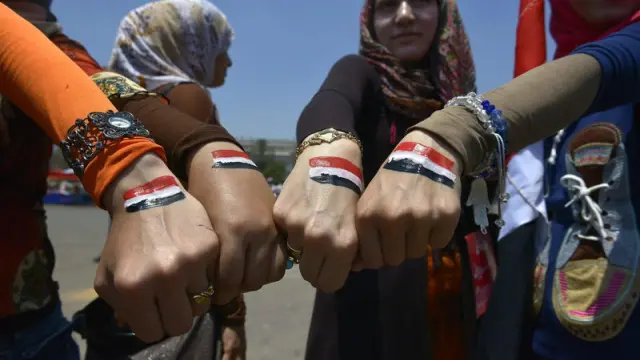 Mujeres egpcias muestran sus manos pintadas con la bandera nacional