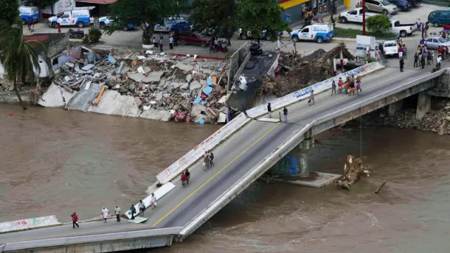 La gente camina por un puente roto en Acapulco