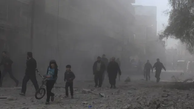 Ciudadanos sirios deambulan entre escombros en los suburbios de Damasco