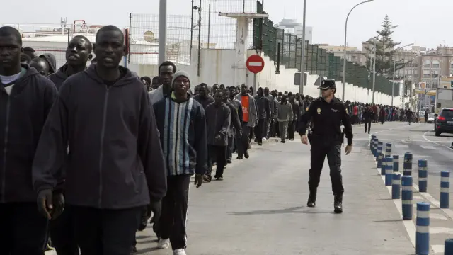 Decenas de inmigrantes subsaharianos camino del CETI de Melilla, tras pasar por la Jefatura Superior de Policía