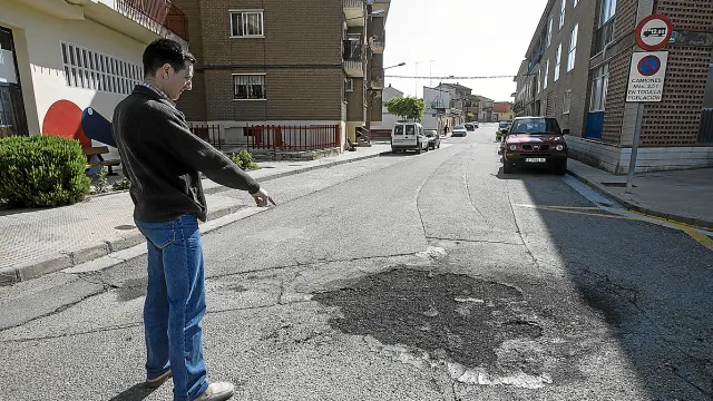 Un comerciante señala el lugar donde el joven quemó el contenedor en la calle Compromiso de Caspe.
