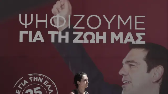 Una mujer pasa por delante de un cartel del líder de SYRIZA