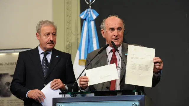Dos representantes del Gobierno argentino muestran la carta la la prensa