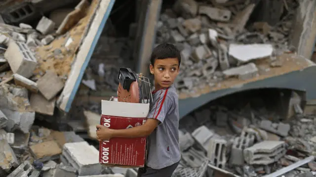 Un niño palestino atraviesa varias casas destruidas en Gaza