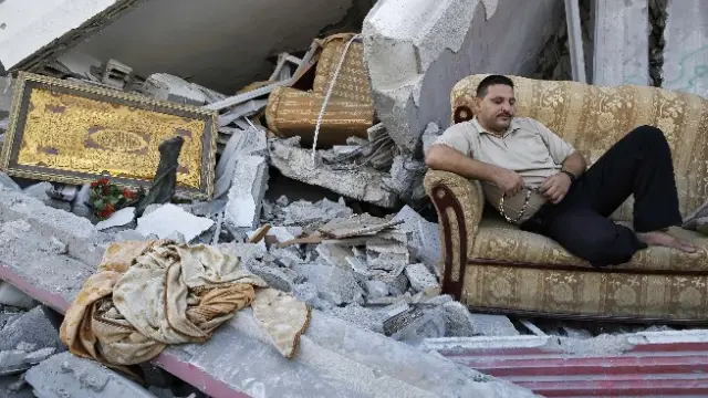 Un palestino descansa junto a los restos de su casa
