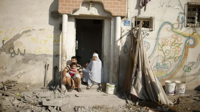 Una familia palestina, en la puerta de su casa dañada por los bombardeos