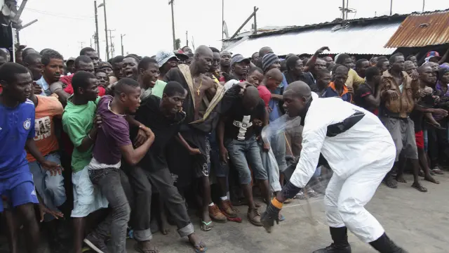 Un policía controla a los residentes en la zona de cuarentena por ébola en Liberia