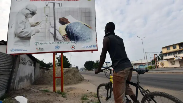 Un hombre observa un cartel: "El riesgo del ébola está todavía ahí"