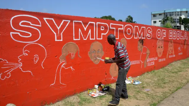 Un artista callejero pinta un mural educativo para informar sobre los síntomas del virus del ébola en las calles de Monrovia.
