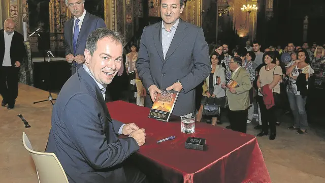 Javier Sierra se dispone a firmar un ejemplar de su última novela al concejal José Manuel Valmaña.