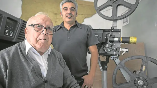 Generoso y Óscar Hernández, delante de un proyector portátil de 35 mm