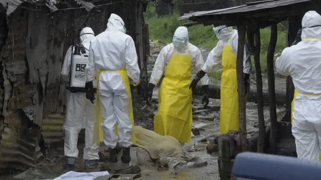 Trabajadores sanitarios se preparan para trasladar el cuerpo de un fallecido de ébola en Monrovia.