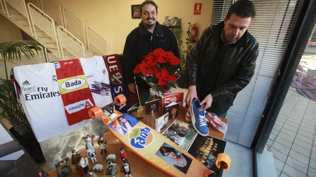 Jaime Esparrach y Carlos Mored, con los regalos de la campaña expuestos en el escaparate de HERALDO.