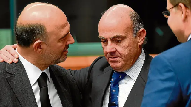 Luis de Guindos, entre los comisarios Moscovici (izquierda) y Dombroskis (derecha).